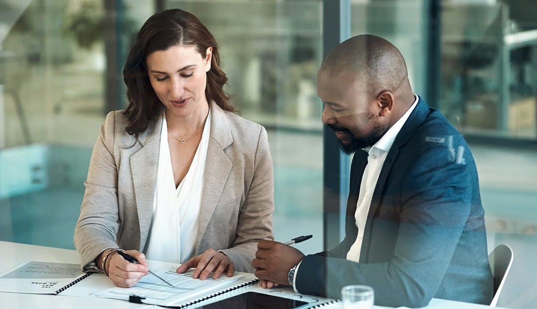 Two people sitting at a table going over paperwork