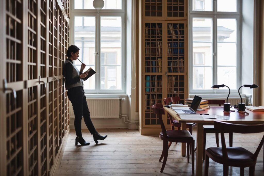 A legal researcher stands and reads a book in a law library.