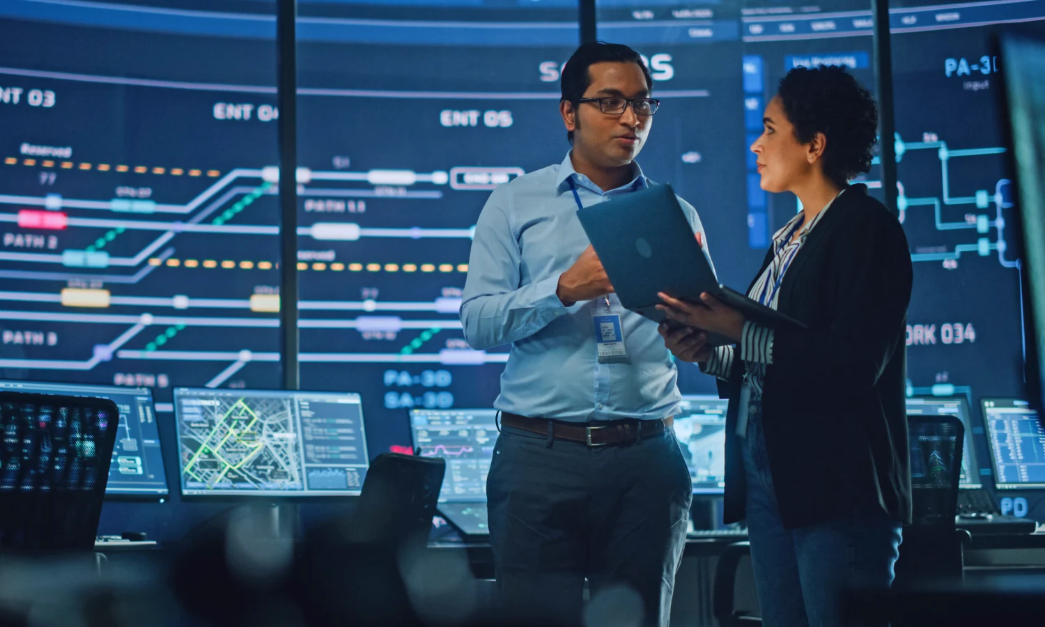 Two law colleagues consult a laptop with a graphic of a engineering system shown in the background.