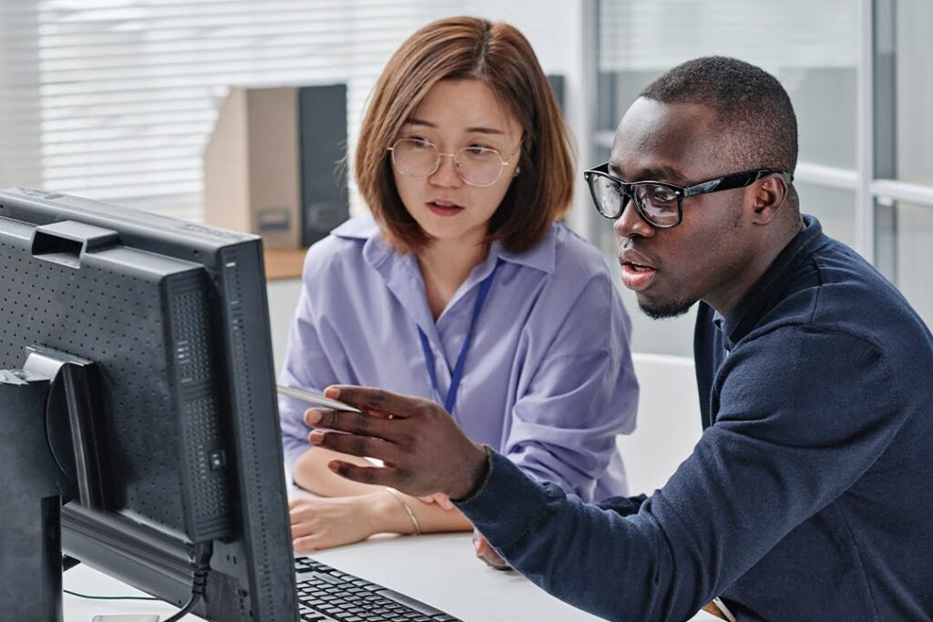Two colleagues collaborate at a computer.